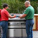 Ember & Stone Customs team installing a large custom BBQ unit into an outdoor kitchen.